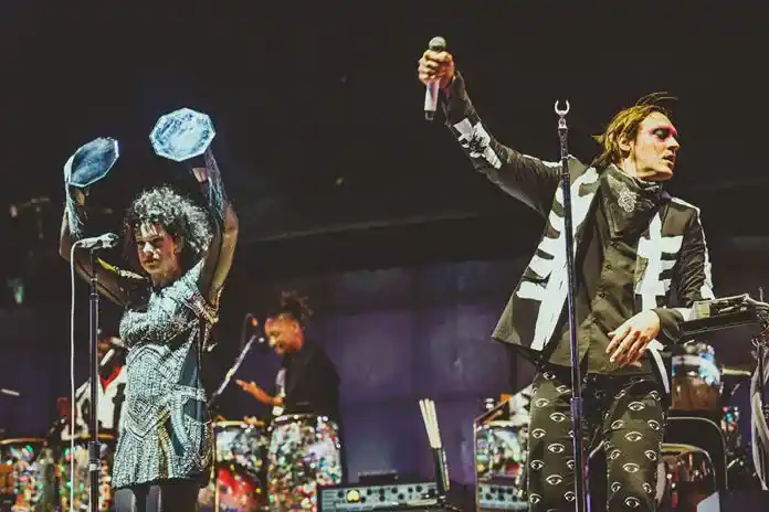 3 integrantes da banda Arcade Fire durante um show e se apresentam no Lollapalooza Brasil 2024